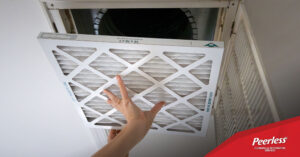 Person removing dirty air filter from their air duct, HVAC, system. Peerless Cleaning & Restoration Services - Air Duct Cleaning