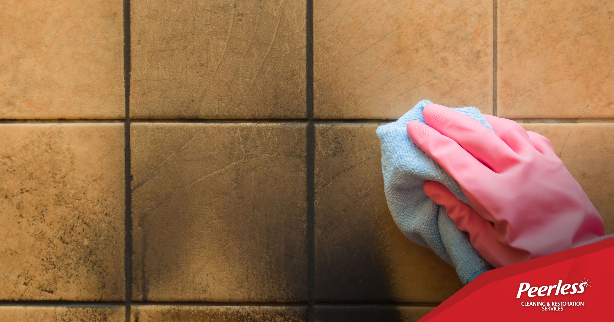 Hand in glove with rag wiping down tile wall to remove soot from fire damage. Peerless Cleaning & Restoration Services - Fire Damage Restoration